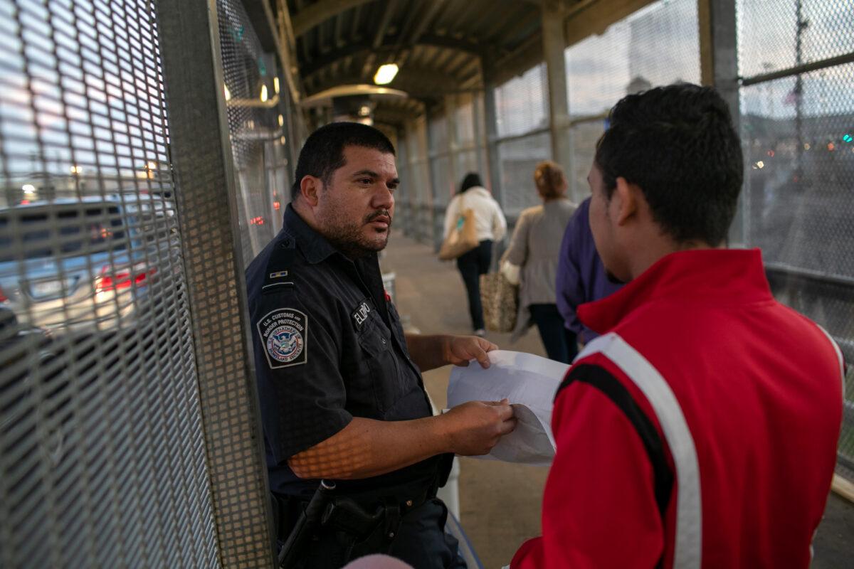 A U.S. Customs and Border Protection officer checks immigration documents as a Honduran asylum seeker arrives to the international bridge from Mexico to the United States next to the border town of Matamoros, Mexico, on Dec. 9, 2019. (John Moore/Getty Images)