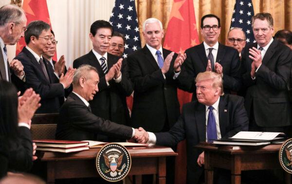 Chinese Vice Premier Liu He (L) and President Donald Trump during the signing of phase one of a trade deal, surrounded by officials, in the East Room of the White House in Washington on Jan. 15, 2020. (Charlotte Cuthbertson/The Epoch Times)