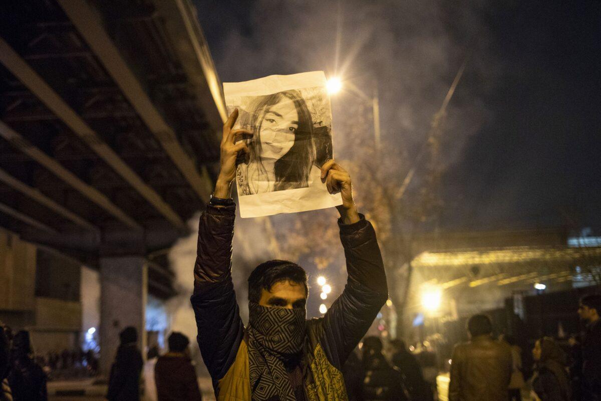 An Iranian man holds a picture of a victim of the Ukrainian 752 flight crash during a demonstration in front of Tehran's Amir Kabir University on Jan. 11, 2020. (STR/AFP via Getty Images)