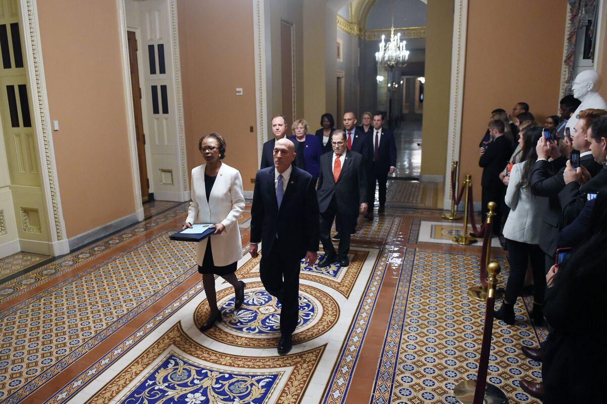 The impeachment articles signed by House Speaker Nancy Pelosi are being carried out by the House SAA Paul Irving, right, and House clerk Cheryl Johnson, left, over to the Senate side followed by impeachment managers on Capitol Hill in Washington on Jan. 15, 2020. (Olivier Douliery/AFP via Getty Images)
