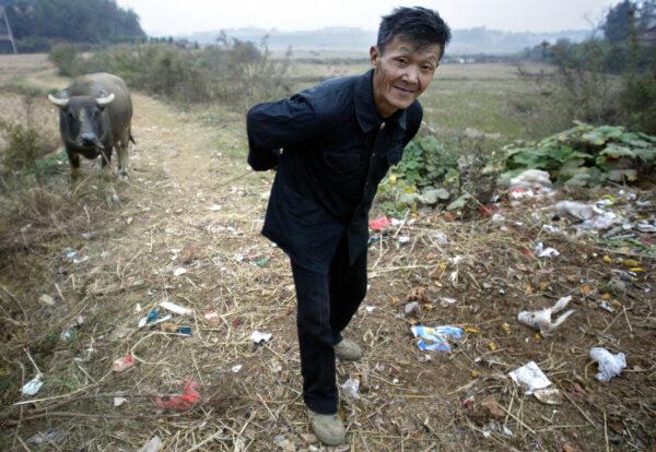 A farmer pulls his water buffalo along garbage-strewn trails in a village outside of Yueyang, in central China's Hunan Province, on Oct. 30, 2004. (Frederic J. Brown/AFP via Getty Images)