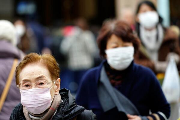 Pedestrians wear protective masks as they walk through a shopping district in Tokyo, Japan, on Jan. 16, 2020. (AP Photo/Eugene Hoshiko)