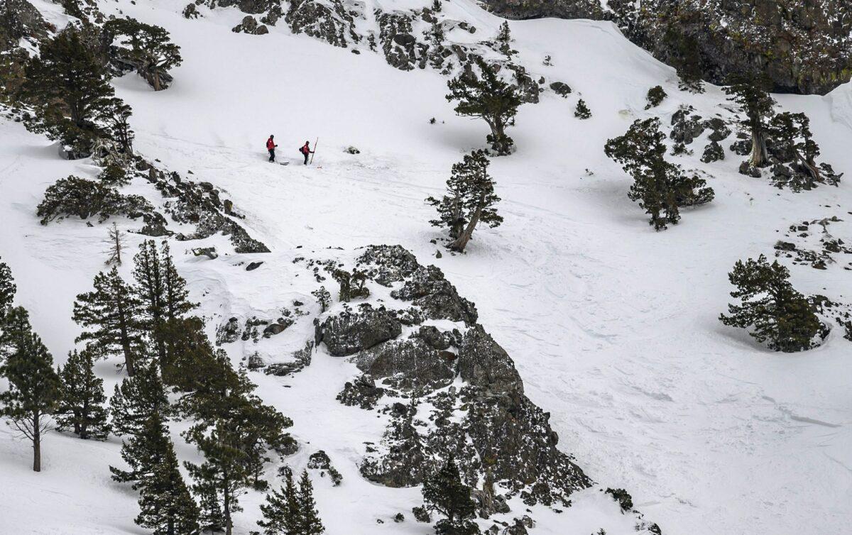 Two members of the ski patrol investigate the top of the avalanche zone on the Subway run where one person was killed and another seriously injured at Alpine Meadows Ski Resort near Lake Tahoe, Calif., on Jan. 17, 2020. (Jason Pierce/The Sacramento Bee via AP)