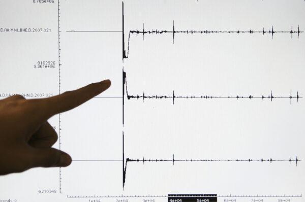File photo of seismologist pointing at a screen graphic of an earthquake (Dimas Ardian/Getty Images)