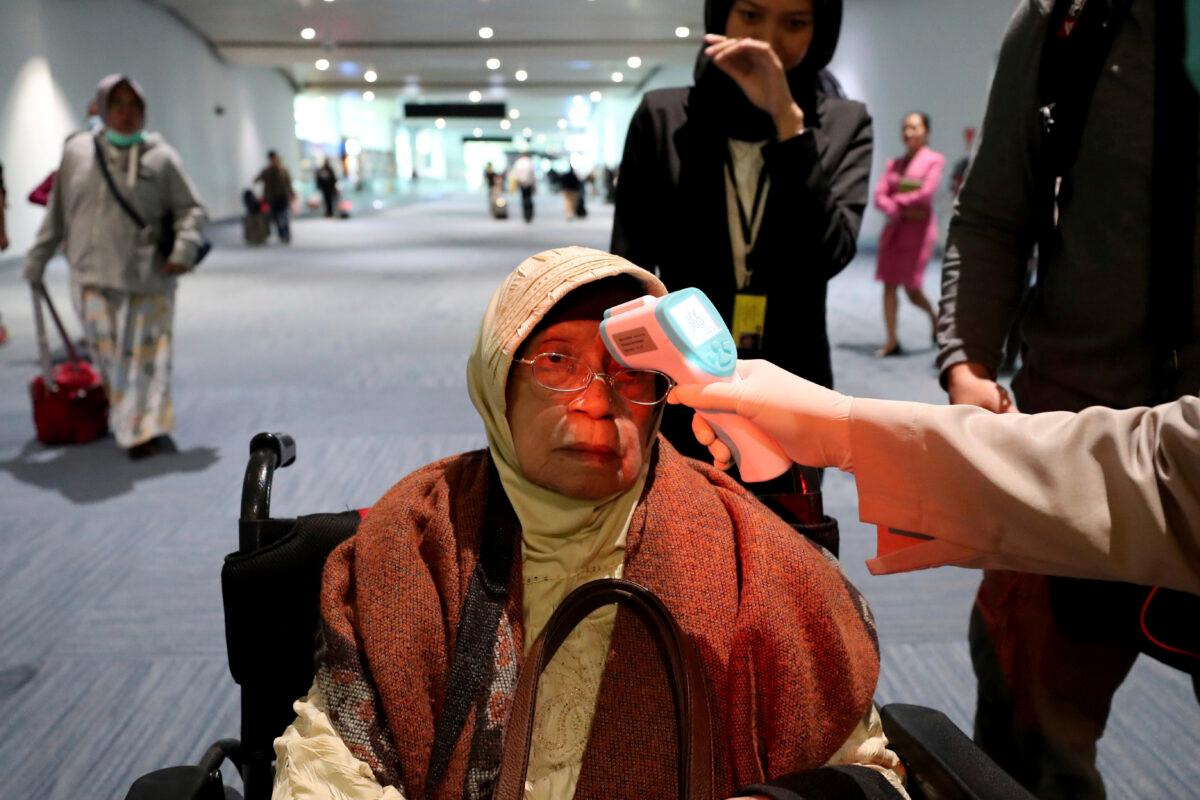A health official scans the body temperature of a passenger as she arrives at the Soekarno-Hatta International Airport in Tangerang, Indonesia, on Jan. 22, 2020. (Tatan Syuflana/AP Photo)
