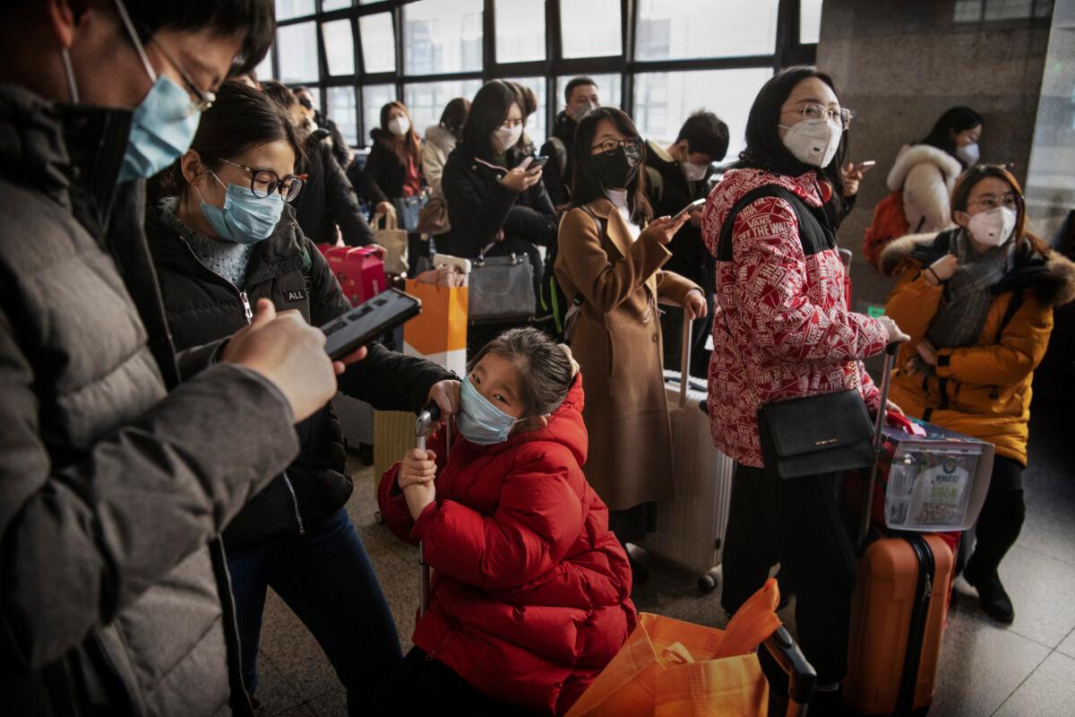Chinese travelers wear protective masks as they wait before boarding a train before the Chinese New Year at a Beijing railway station in Beijing, China on Jan. 23, 2020. (Kevin Frayer/Getty Images)