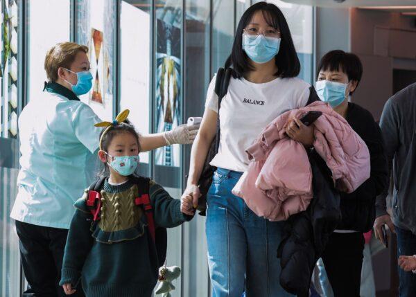 A health officer (L) screens arriving passengers from China at Changi International airport in Singapore on Jan. 22, 2020. (Roslan Rahman/AFP via Getty Images)