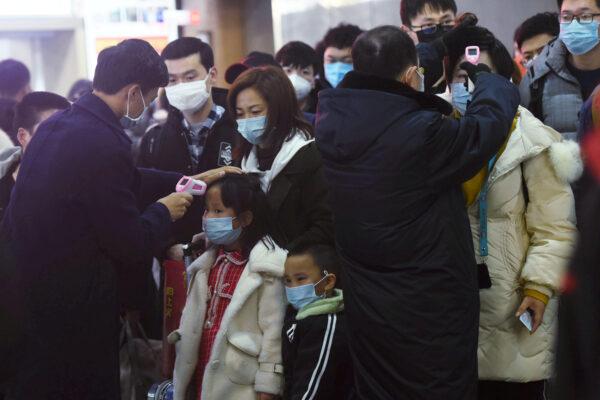 Staff members check body temperatures of passengers arriving from the train from Wuhan to Hangzhou, at Hangzhou Railway Station ahead of the Chinese Lunar New Year in Zhejiang Province, China, on Jan. 23, 2020. (China Daily via Reuters)
