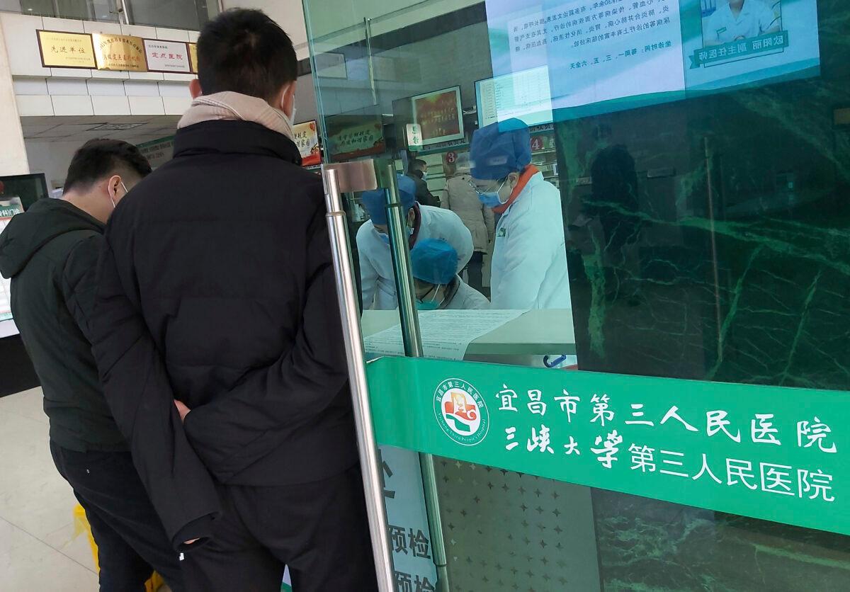 Hospital staff wear face masks as they work at a check-in desk at a hospital that reported a coronavirus death in Yichang in central China's Hubei Province on Jan. 23, 2020. (Chinatopix via AP)