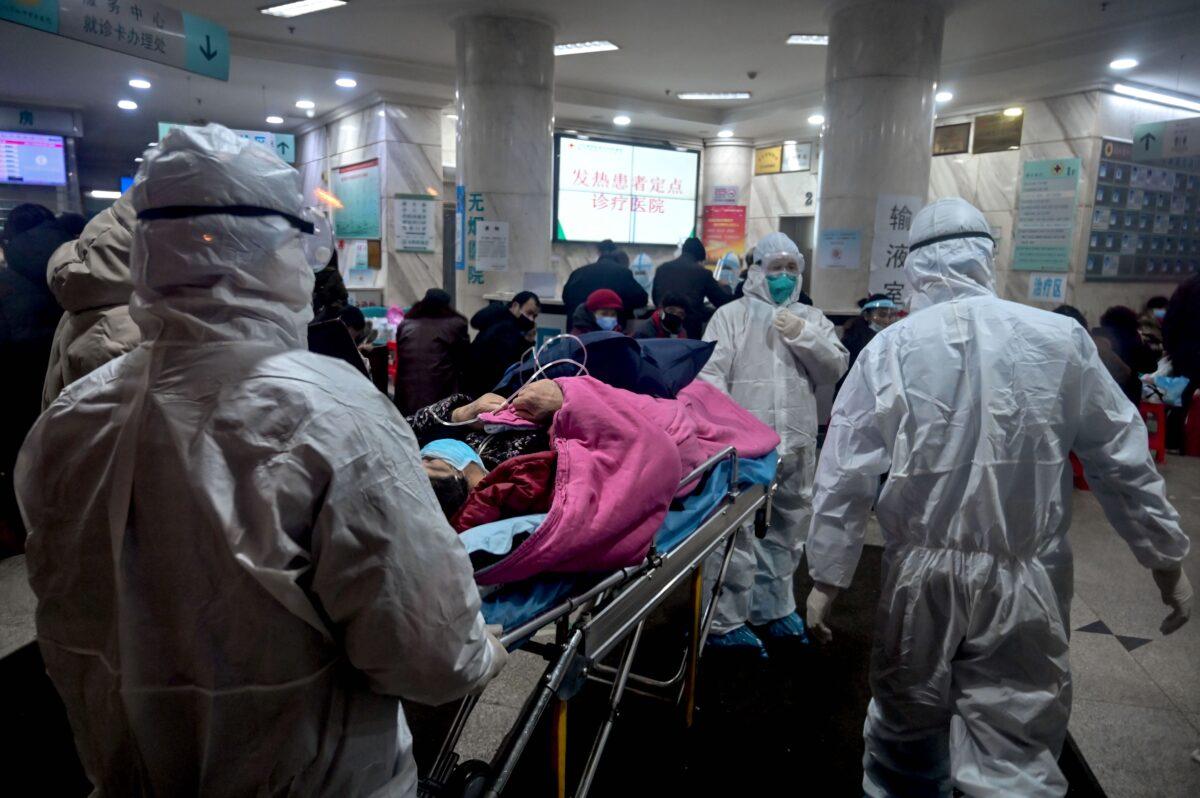 Medical staff wearing protective clothing to protect against a previously unknown coronavirus arrive with a patient at the Wuhan Red Cross Hospital in Wuhan, China, on Jan. 25, 2020. (Hector Retamal/AFP via Getty Images)