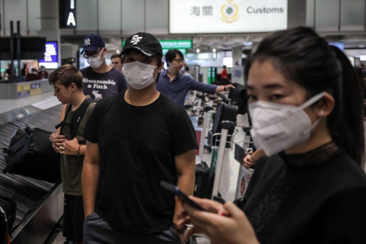 Travelers wearing face masks as a precautionary measure to protect against the outbreak of coronavirus, at Hong Kong International Airport, on Jan. 23, 2020. (Vivek Prakash/AFP via Getty Images)