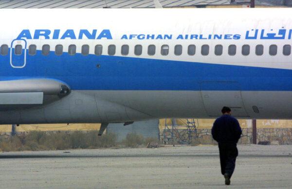 An Afghan man walks towards an Ariana Afghan Airlines plane on the tarmac at the Kabul airport on Jan. 10, 2002 in Kabul, Afghanistan. (Photo by Paula Bronstein/Getty Images)
