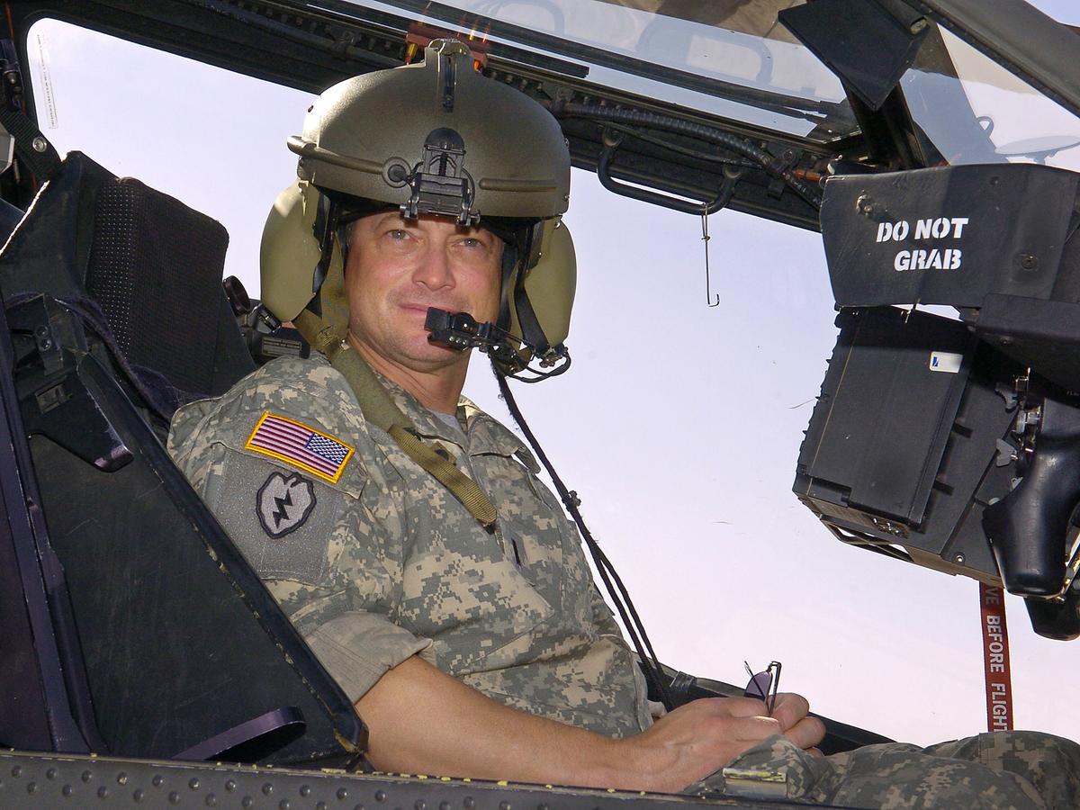 Sinise in a U.S. Army Apache helicopter during a tour of the flight line at the Contingency Operating Base in Speicher, Iraq, on May 21, 2007 (©Getty Images | <a href="https://www.gettyimages.com/detail/news-photo/in-this-handout-provided-by-the-uso-actor-gary-sinise-sits-news-photo/74210351">Mike Theiler/USO</a>)