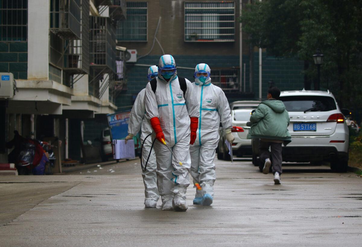 Workers from local disease control and prevention department in protective suits disinfect a residential area following the outbreak of a new coronavirus, in Ruichang, Jiangxi province, China on Jan. 25, 2020. (cnsphoto via Reuters)