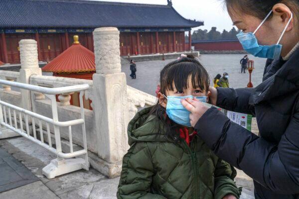 A Chinese woman puts a protective mask on a young girl as they tour the grounds of the Temple of Heaven in Beijing, China, which remained open during the Chinese New Year and Spring Festival holiday on Jan. 27, 2020. (Kevin Frayer/Getty Images)