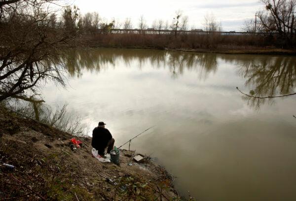 A fisherman sits along the slough where the body of infant Nikko Lee Perez was discovered in Yolo County in 2007, near Woodland, Calif., on Jan. 27, 2020. (Rich Pedroncelli /AP Photo)