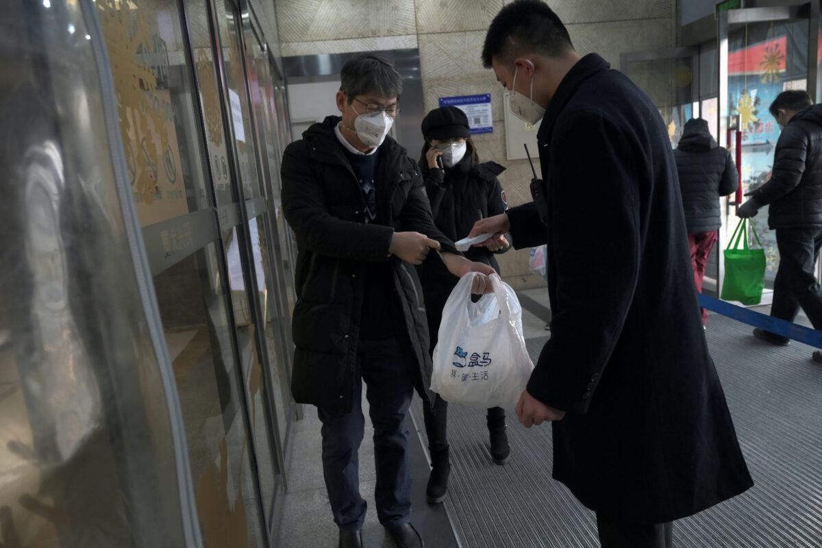 Security personnel checks the temperature of a customer entering Alibaba's Hema Fresh chain store, following the coronavirus outbreak, during the Chinese Lunar New Year holiday, in Beijing, China January 27, 2020. (Tingshu Wang/Reuters)