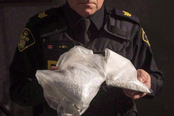 An Ontario Provincial Police officer displays bags containing fentanyl during a news conference in Vaughan, Ont., on Feb. 23, 2017. (The Canadian Press/Chris Young)