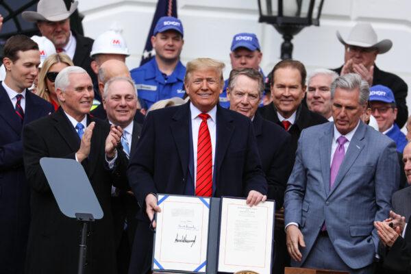 President Donald Trump holds up the signed United States–Mexico–Canada Agreement, known as USMCA, during a ceremony on the South Lawn of the White House on Jan. 29, 2020. (Charlotte Cuthbertson/The Epoch Times)