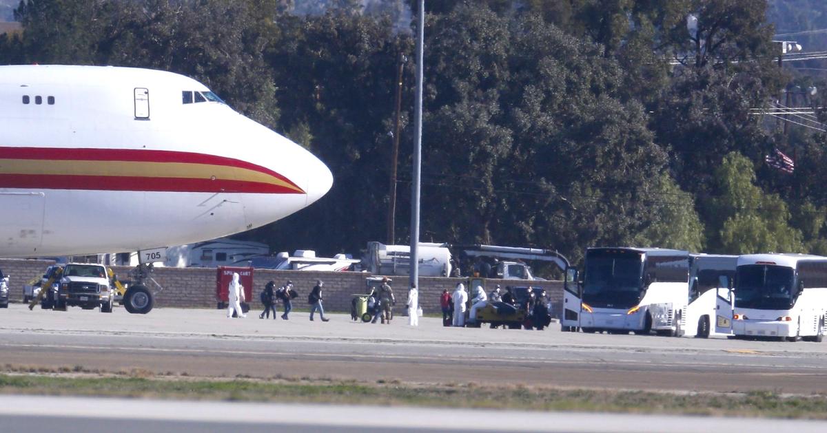 Passengers board buses after arriving on an airplane carrying U.S. citizens being evacuated from Wuhan, China, at March Air Reserve Base in Riverside, Calif., on Jan. 29, 2020. (Ringo H.W. Chiu/AP Photo)