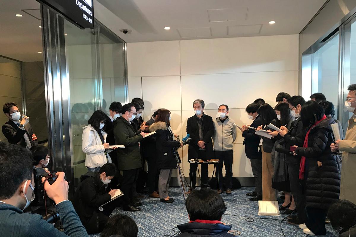Takeo Aoyama, center left, an employee at Nippon Steel Corp.’s subsidiary in Wuhan, China, and Takayuki Kato, center right, an employee at an information and communications technology company Intec, speak to journalists, all wearing protective face masks, after returning home by a Japanese chartered plane at Haneda international airport in Tokyo, Japan on Jan. 29, 2020. (Haruka Nuga/AP)