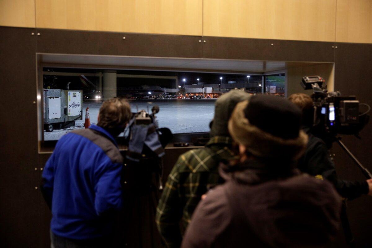 Members of the media watch as a plane chartered by the U.S. State Department to evacuate government employees and other Americans from the novel coronavirus threat in the Chinese city of Wuhan, is seen on the tarmac after arriving at a closed terminal at Ted Stevens Anchorage International Airport in Anchorage, Alaska on Jan. 28, 2020. (Kerry Tasker/Reuters)