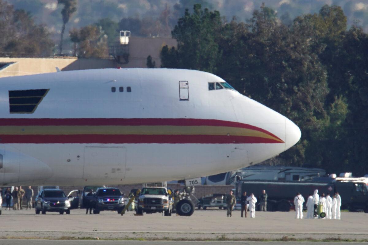 Personnel in protective clothing approach an aircraft, chartered by the U.S. State Department to evacuate government employees and other Americans from the novel coronavirus threat in the Chinese city of Wuhan, after it arrived at March Air Reserve Base in Riverside County, California on Jan. 29, 2020. (Mike Blake/Reuters)