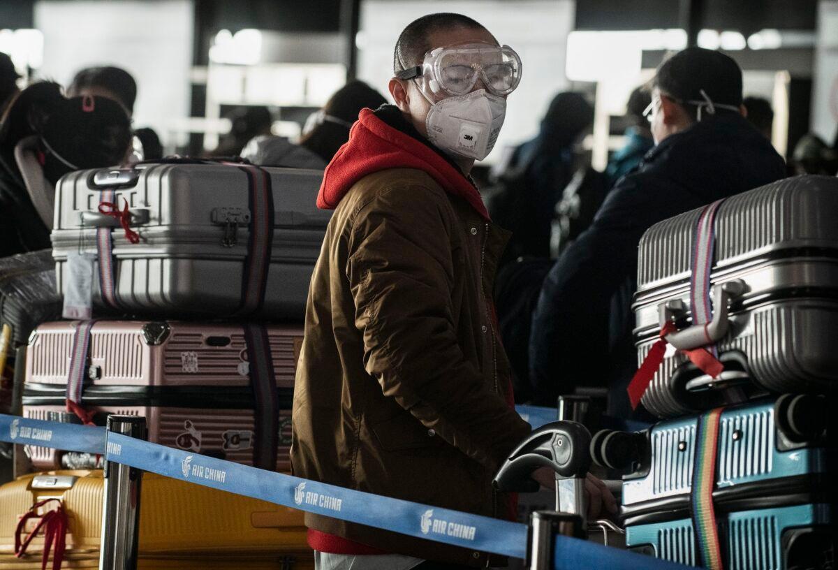 A man wears a protective mask and goggles as he lines up to check in to a flight at Beijing Capital Airport on Jan. 30, 2020. (Kevin Frayer/Getty Images)