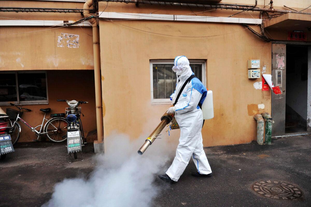 A worker wearing a protective suit sprays disinfectant in a neighborhood in Qingdao in eastern China's Shandong Province on Jan. 28, 2020. (Chinatopix via AP)