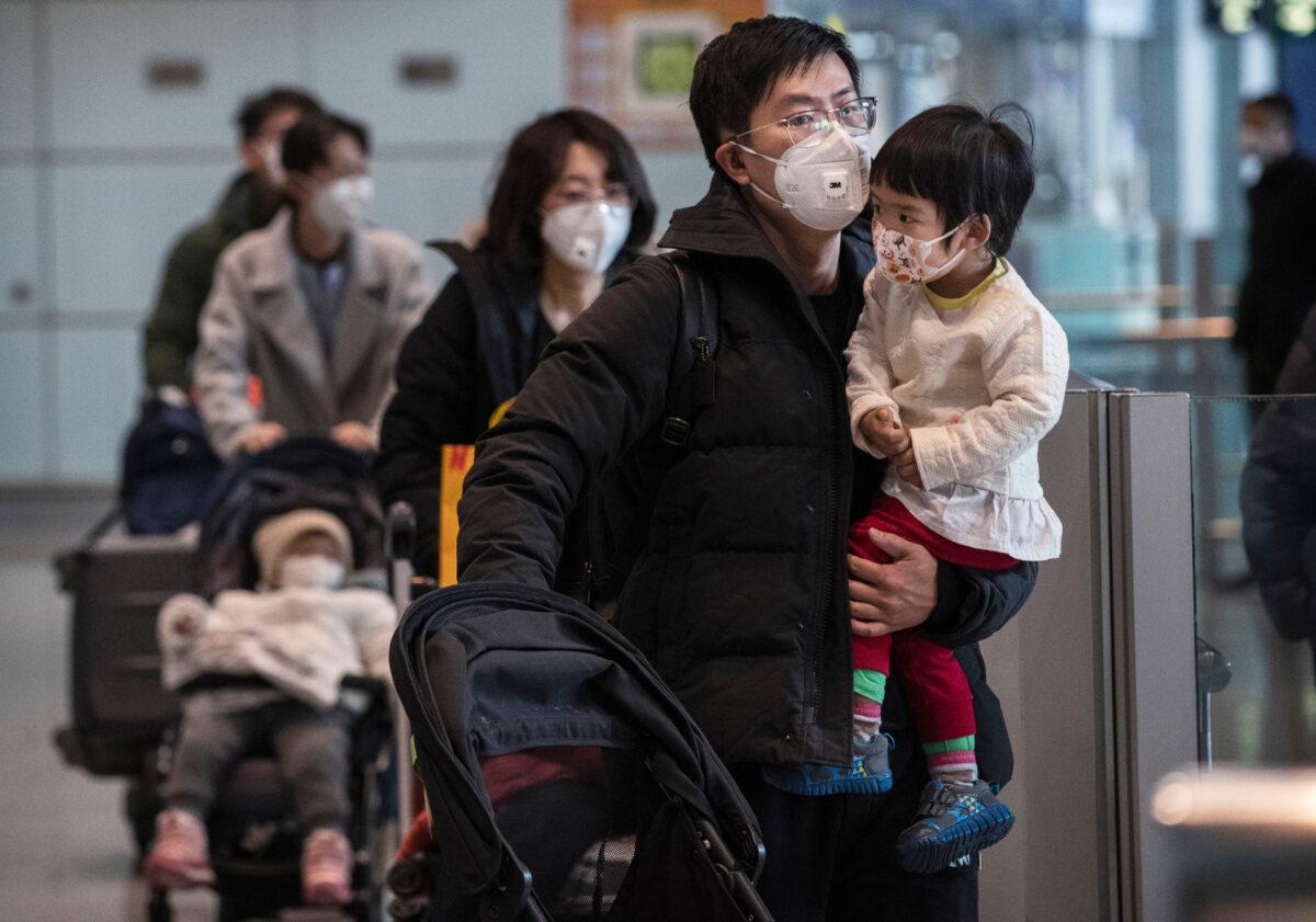 Passengers wear protective masks as they walk with their luggage in the arrivals area at Beijing Capital Airport in Beijing, China, on Jan. 30, 2020.(Kevin Frayer/Getty Images)