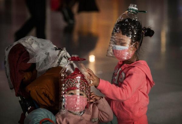 Chinese children wear plastic bottles as makeshift homemade protection and protective masks while waiting to check in to a flight at Beijing Capital Airport on Jan. 30, 2020. (Kevin Frayer/Getty Images)