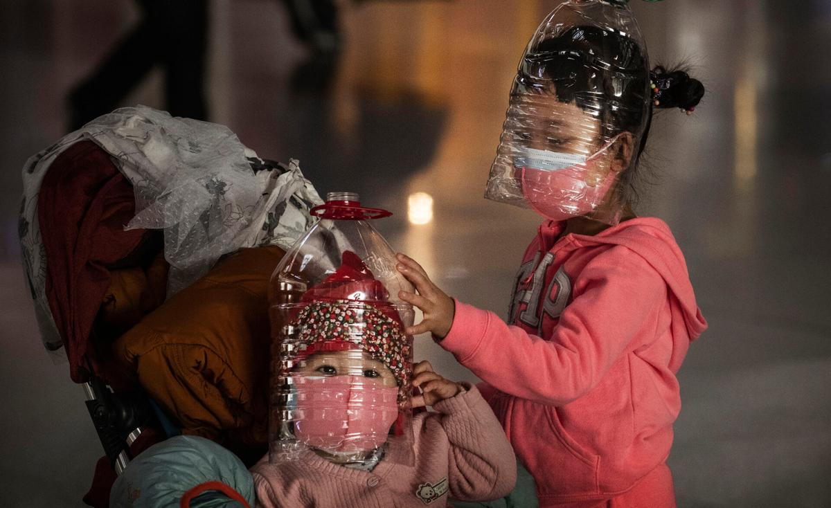 Chinese children wear plastic bottles as makeshift homemade protection and protective masks while waiting to check in to a flight at Beijing Capital Airport in Beijing, China, on Jan. 30, 2020. (Kevin Frayer/Getty Images)
