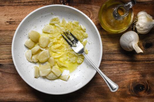 Mashing softened garlic cloves with olive oil. (Audrey Le Goff)