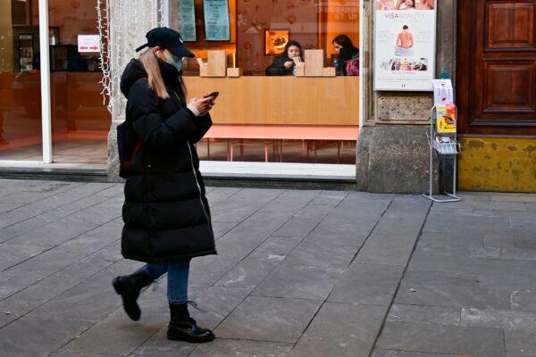 A woman wearing a mask checks her smartphone in via Paolo Sarpi, the commercial street of the chinese district of Milan on Jan. 30, 2020. (MIGUEL MEDINA/AFP via Getty Images)