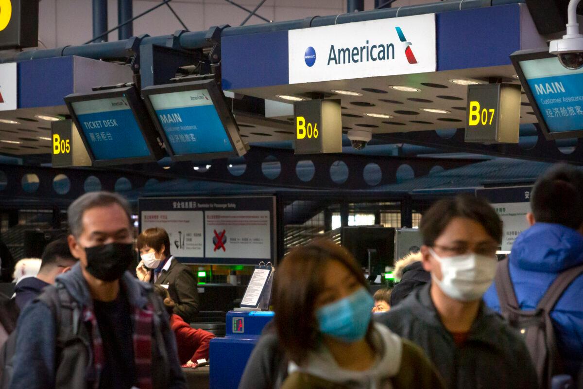 Travelers wearing face masks line up to check in for an American Airlines flight to Los Angeles at Beijing Capital International Airport in Beijing on Jan. 30, 2020. (Mark Schiefelbein/AP Photo)
