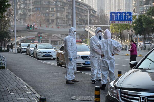 Chinese officials in protective suits checking on an elderly man wearing a facemask who collapsed and died on a street near a hospital in Wuhan, China, on Jan. 30, 2020. AFP journalists saw the body not long before an emergency vehicle arrived carrying police and medical staff in full-body protective suits. (HECTOR RETAMAL/AFP via Getty Images)
