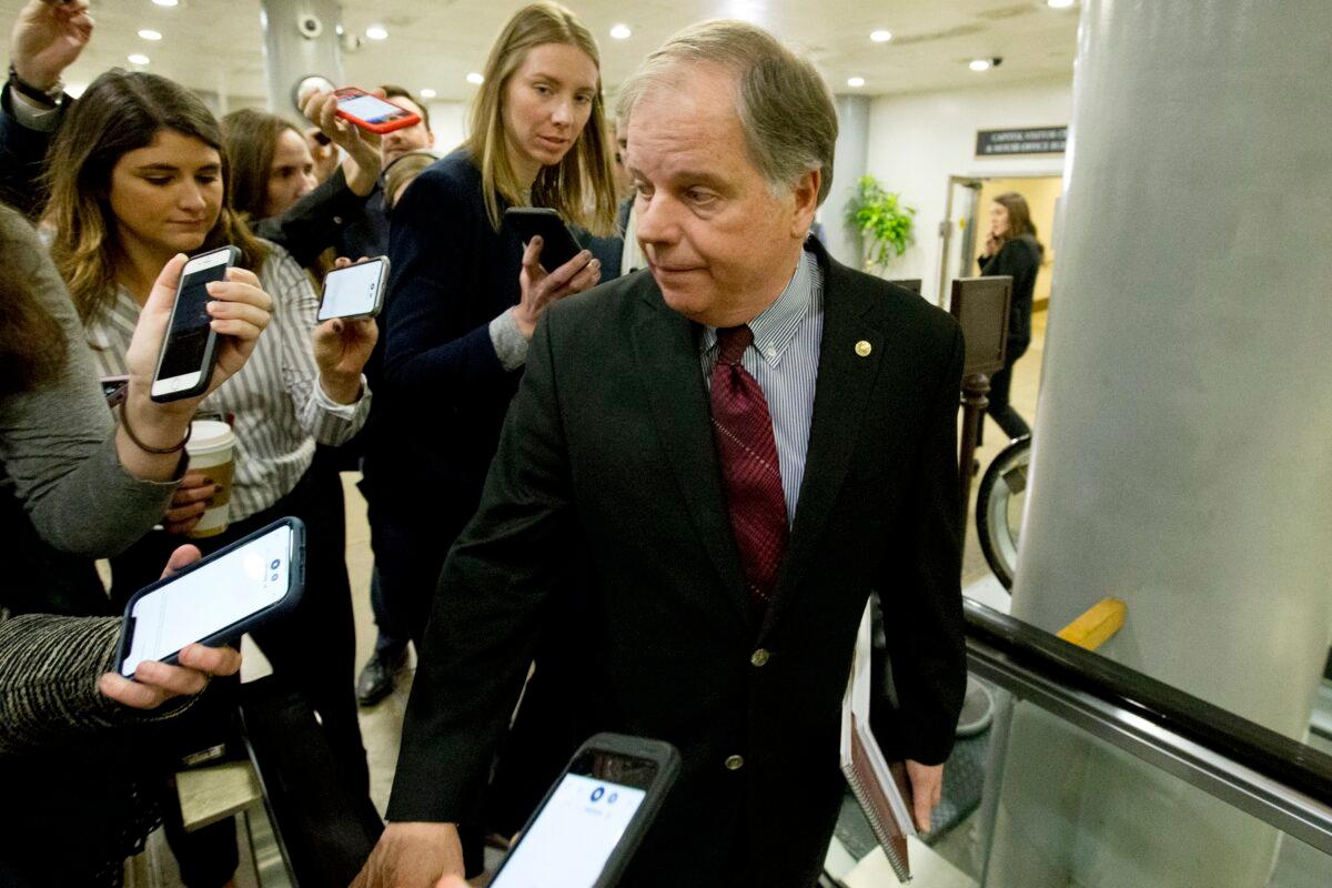 Sen. Doug Jones (D-Ala.) talks to reporters as he walks to attend the impeachment trial of President Donald Trump on charges of abuse of power and obstruction of Congress on Capitol Hill in Washington on Jan. 28, 2020. (Jose Luis Magana/AP Photo)