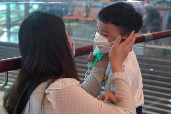 A woman wearing a mask helps her son put on his mask at Changi Airport in Singapore on Jan. 25, 2020. (Ore Huiying/Getty Images)