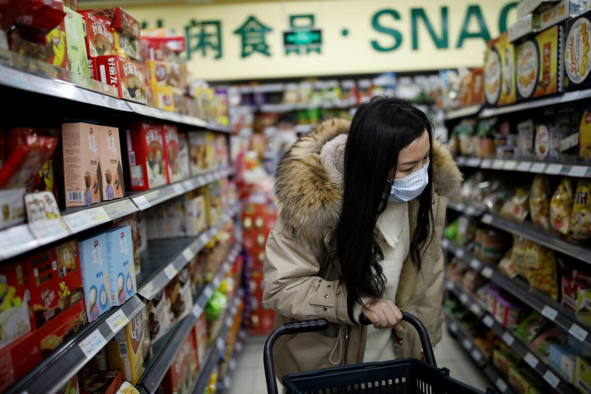 A woman wearing a face mask looks for products at a supermarket, as the country is hit by an outbreak of the new coronavirus, in Beijing, China on Jan. 31, 2020. (Carlos Garcia Rawlins/Reuters)
