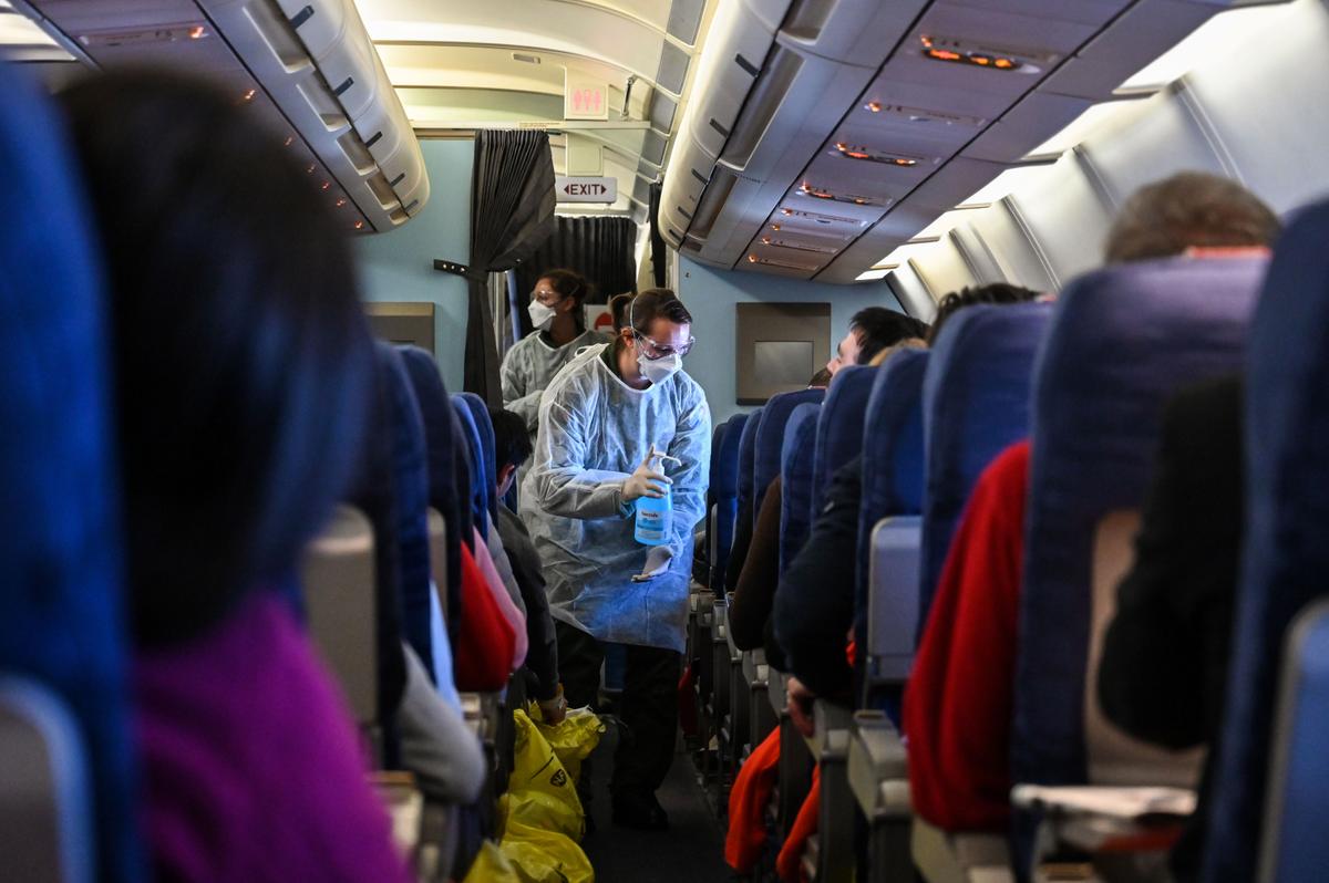 A crew member of an evacuation flight of French citizens from Wuhan gives passengers disinfectant during the flight to France on Feb. 1, 2020. (Hector Retamal/AFP via Getty Images)