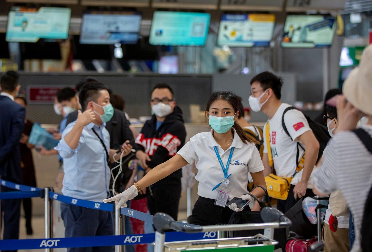 An airline staffer guides Chinese tourists from Wuhan standing in line to get a seat to return to Wuhan, China, at Suvarnabhumi airport in Bangkok, Thailand, on Jan. 31, 2020. (Gemunu Amarasinghe/AP)