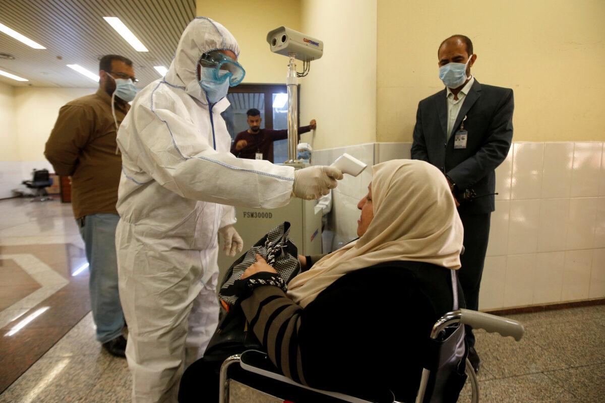 An Iraqi Health Ministry employee checks a passenger's temperature, amid the new coronavirus outbreak, upon their arrival at Basra airport, in Basra, Iraq, on Feb. 1, 2020. (Essam al-Sudani/Reuters)