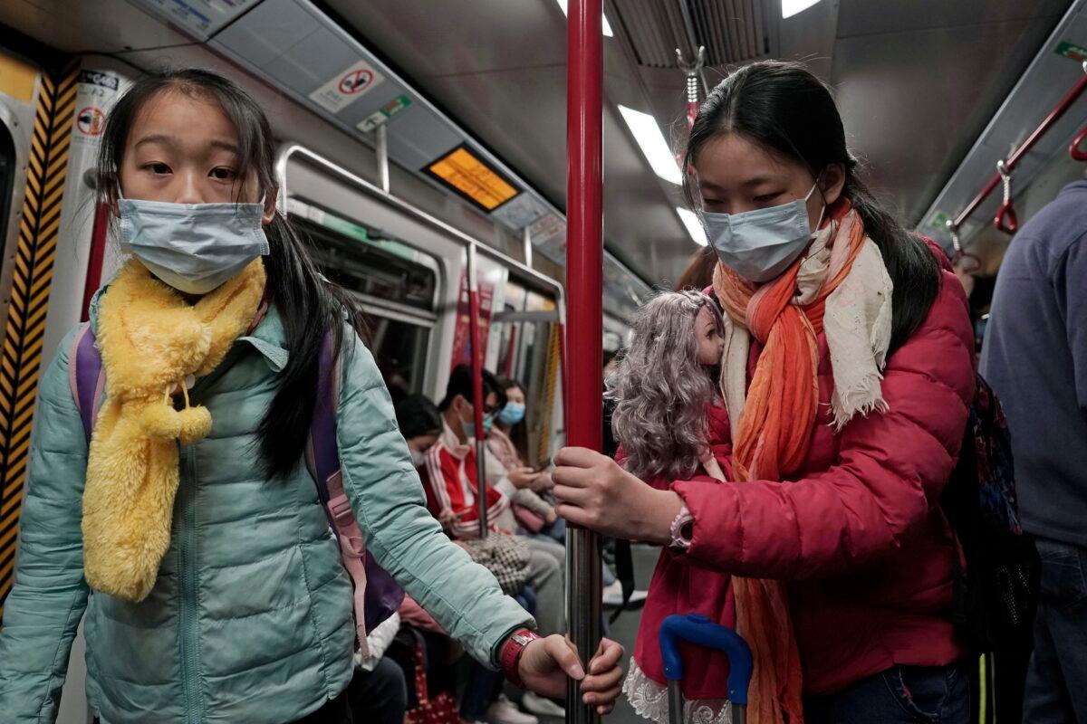 Two girls with face masks ride the subway in Hong Kong on Feb. 1, 2020. (Kin on Cheung/AP Photo)