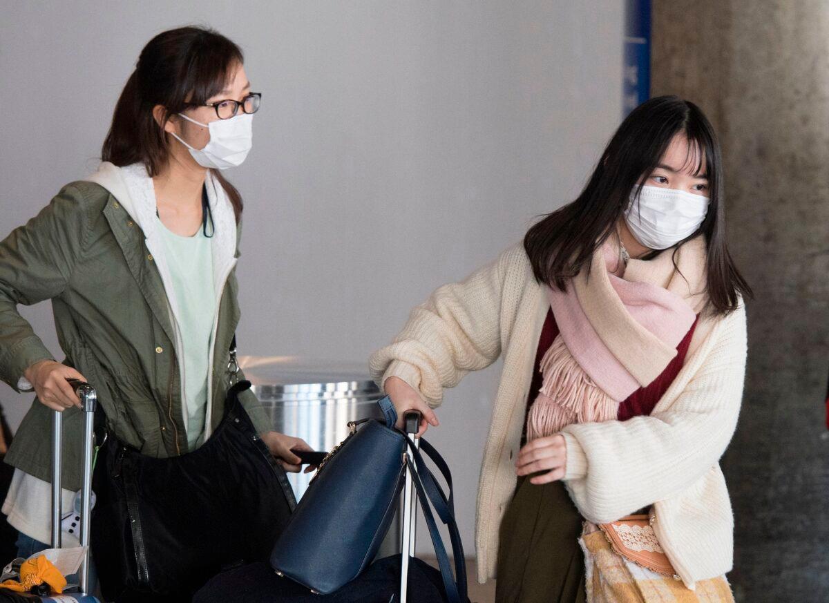 Passengers wear face masks to protect against the spread of the Coronavirus as they arrive on a flight from Asia, at Los Angeles International Airport, Calif., on Feb. 1, 2020. (Mark Ralston/AFP via Getty Images)