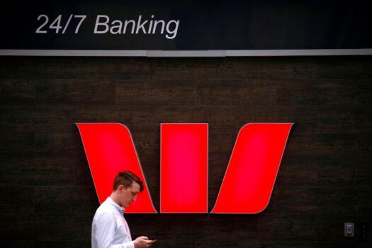 A pedestrian looks at his phone as he walks past a logo for Australia's Westpac Banking Corp located outside a branch in central Sydney, Australia, on Nov. 5, 2018. (David Gray/Reuters/File Photo)