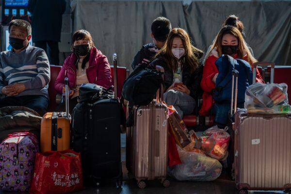 People wearing protective masks wait to board their train as they travel for the Lunar New Year holidays at the Beijing West Railway Station in Beijing on Jan. 24, 2020. (Nicolas Asfouri/AFP via Getty Images)