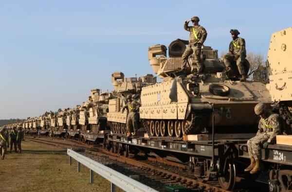 Members of the U.S. Army 1st Division 9th Regiment 1st Battalion unload heavy combat equipment including Abrams tanks and Bradley fighting vehicles at the railway station near the Pabrade military base in Lithuania, on October 21, 2019. (Petras Malukas / AFP via Getty Images)