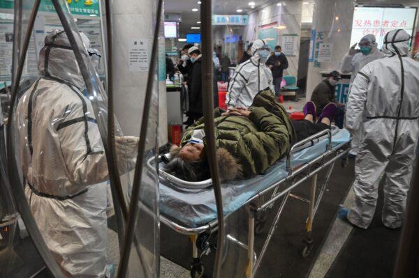 Medical staff members wearing protective clothing arrive with a patient at the Wuhan Red Cross Hospital in Wuhan, China, on Jan. 25, 2020. (Hector Retamal/AFP via Getty Images)