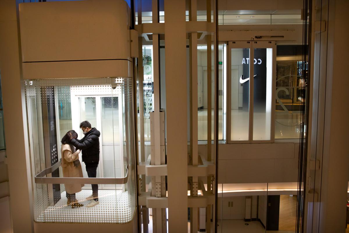 A couple wearing face masks ride an elevator at a nearly empty shopping mall in Beijing, China on Jan. 29, 2020. (Mark Schiefelbein/AP)
