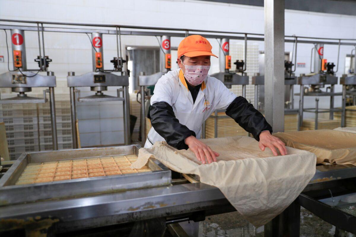 A worker wearing a face mask works on a production line manufacturing soybean-based food products at a factory in Hefei, Anhui province, China on Feb. 4, 2020. (China Daily via Reuters)